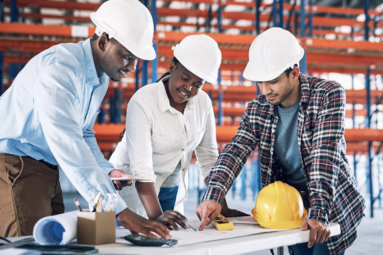 Three people standing over blueprints